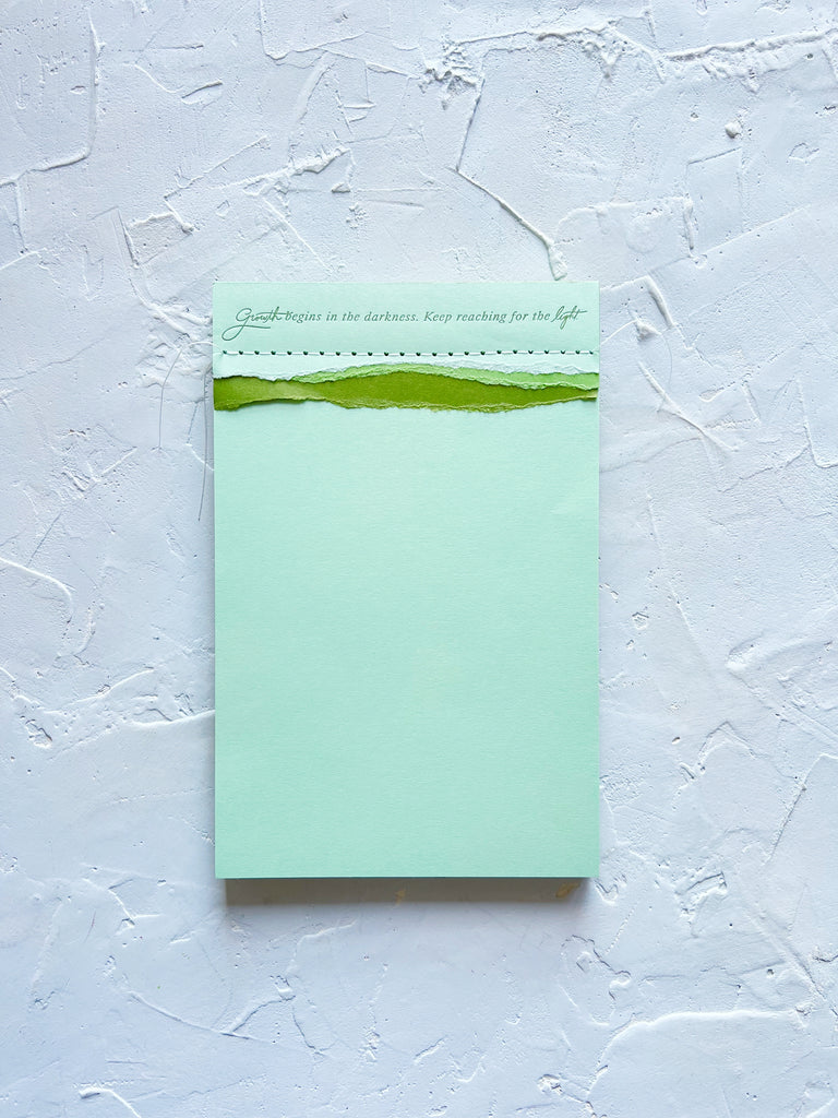 tri-color green shades notepad that says growth begins in the darkness. keep reaching for the light.