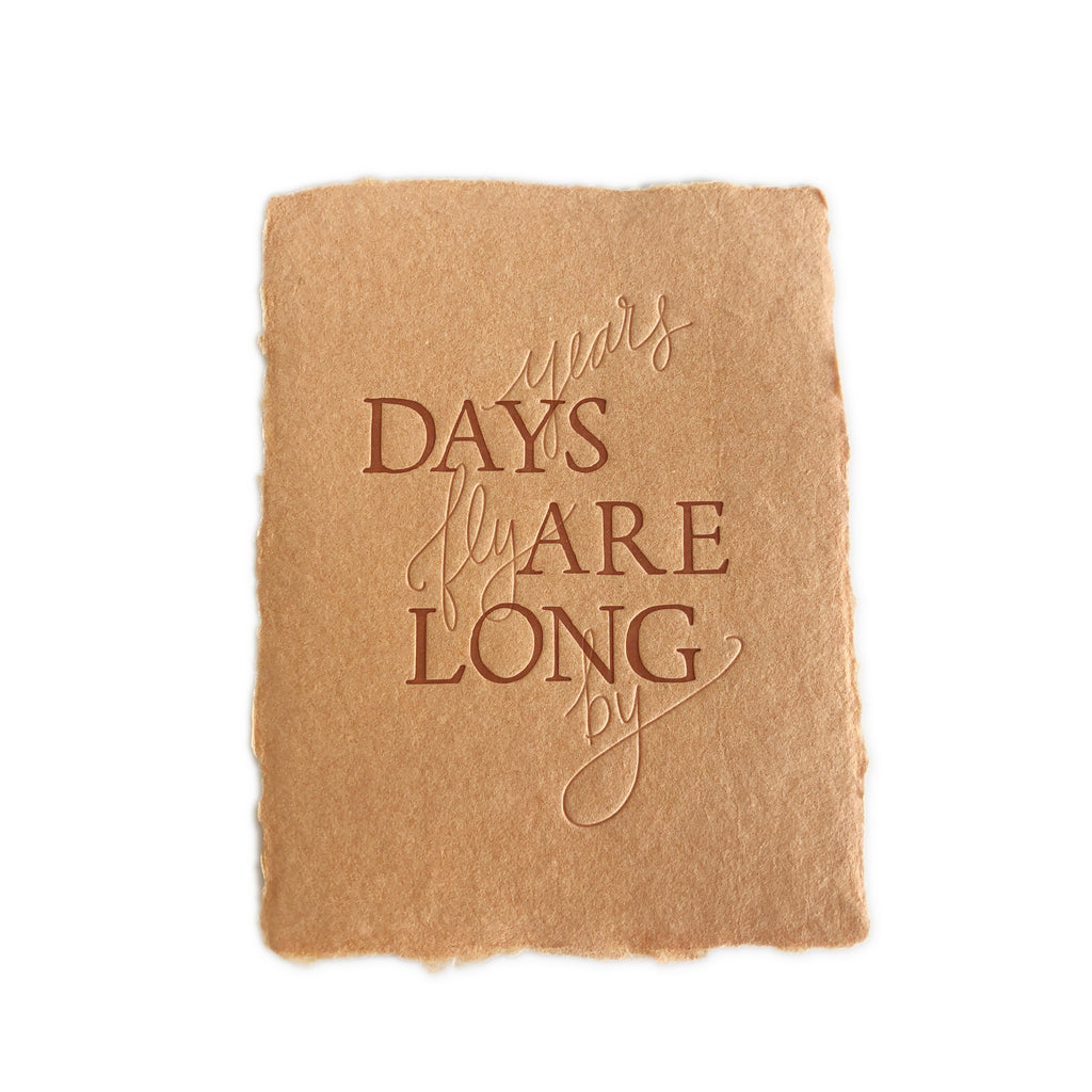 Tan brown card with torn edges with brown text saying, “Days Are Long Years Fly By”. A matching envelope is included.
