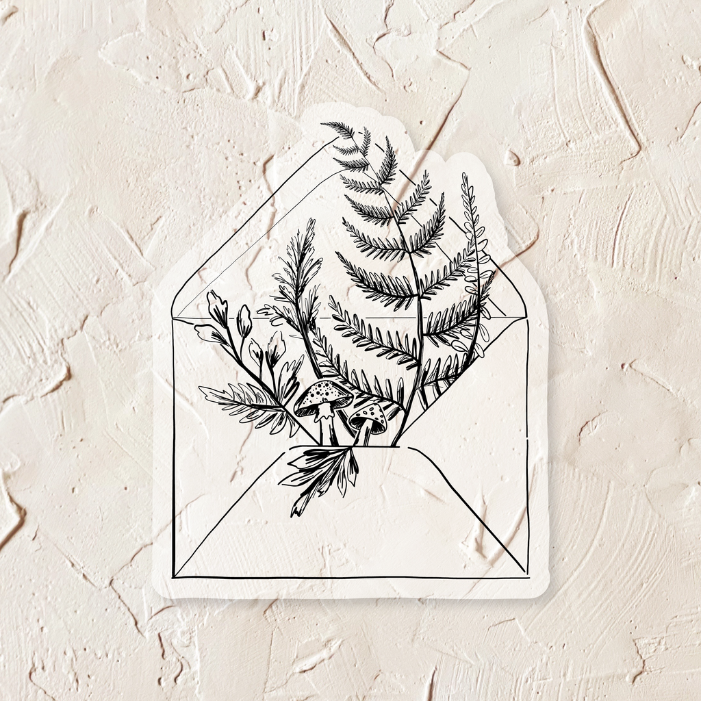 Black and white sticker in the image of an envelope with greenery and mushrooms coming out of back flap.