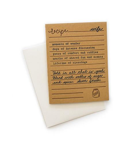 Brown card with black and brown text saying, “Recipe for Wife: moments of wonder; days of intense discussion; years of comfort and cuddles; months of shared fun and events; lifetime of blessings. Fold in all that is good. Blend with oodles of sugar and spice. Savor forever.” Image of a jar of sugar in bottom right corner. A white envelope is included.