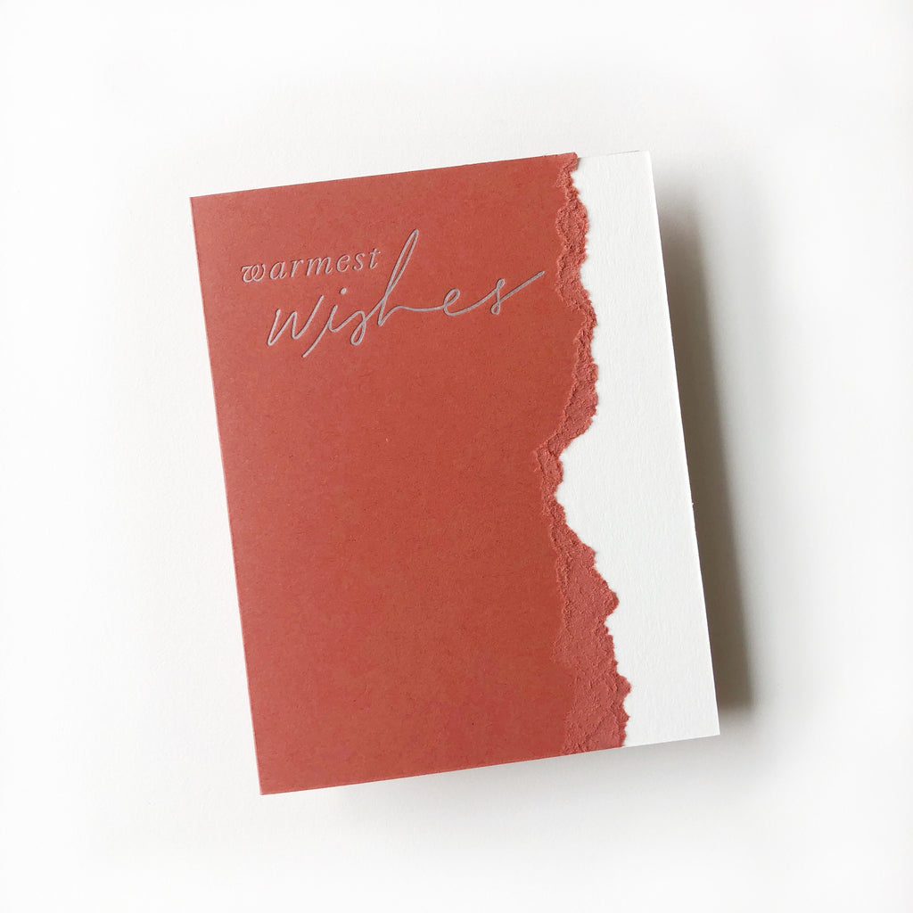 Red card with white torn edge on right side. Silver text saying, “Warmest Wishes”. A matching envelope is included.