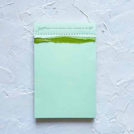 tri-color green shades notepad that says growth begins in the darkness. keep reaching for the light.